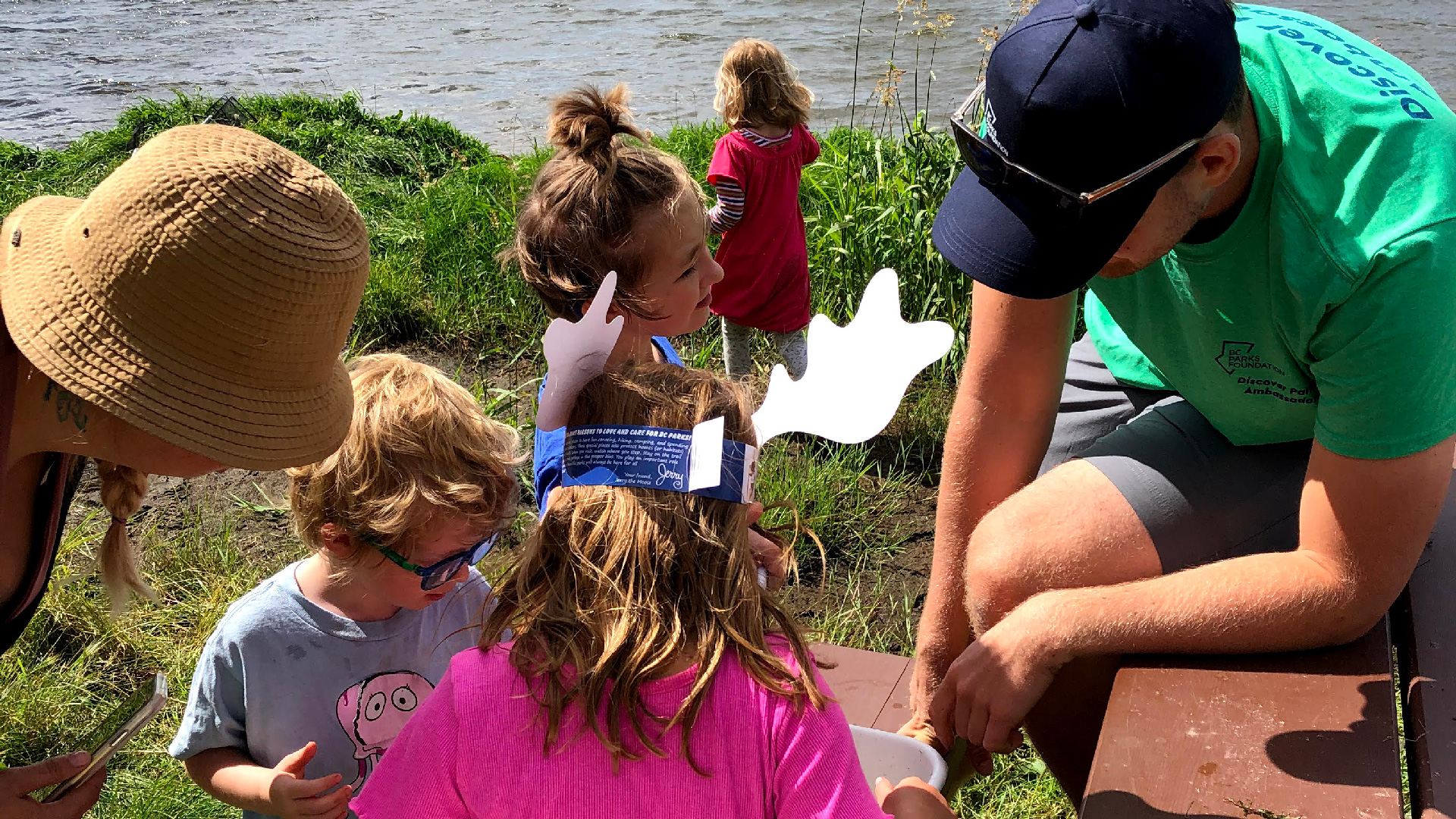 Adults from the CLCS looking on and helping children doing science experiments to learn about Charlie Lake and the watershed.